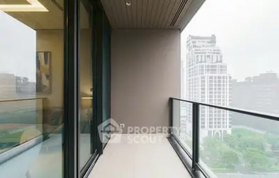Spacious balcony with glass railing offering stunning city views in modern high-rise apartment.