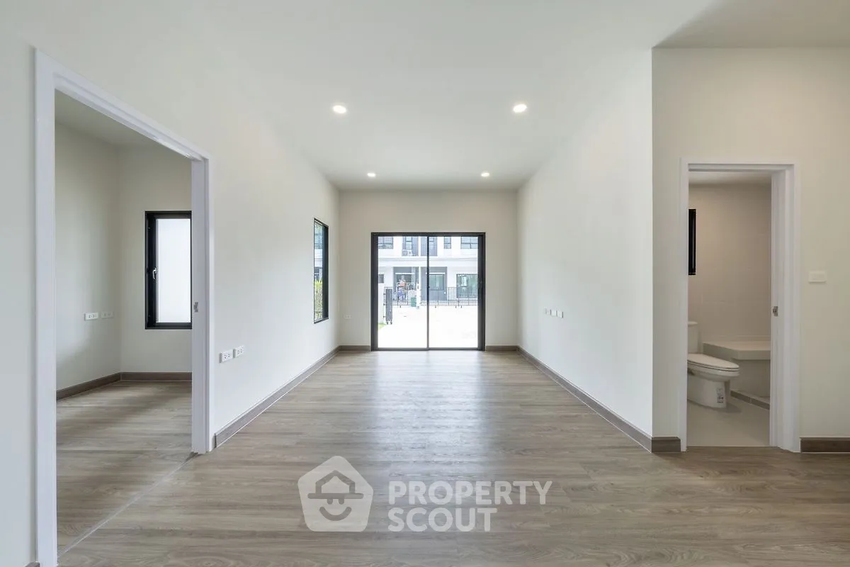 Spacious modern interior with wooden flooring and large windows, ideal for customization.