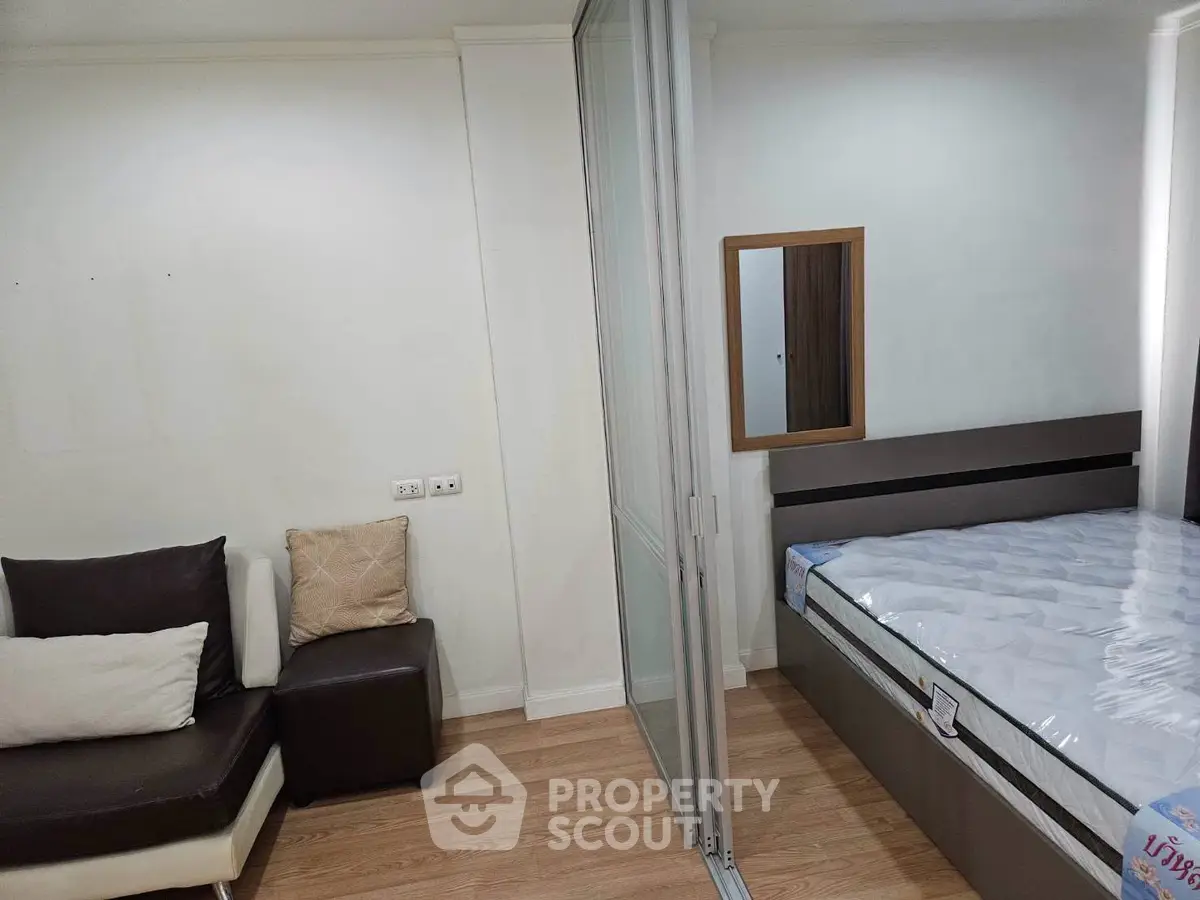 Modern bedroom with sliding glass partition and cozy seating area, perfect for urban living.
