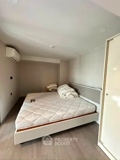 Modern bedroom with minimalist design and air conditioning, featuring a comfortable bed and sleek flooring.