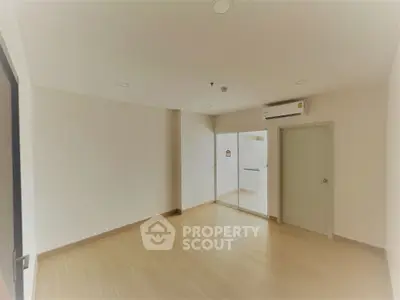 Spacious empty room with wooden flooring and air conditioning, ideal for customization.