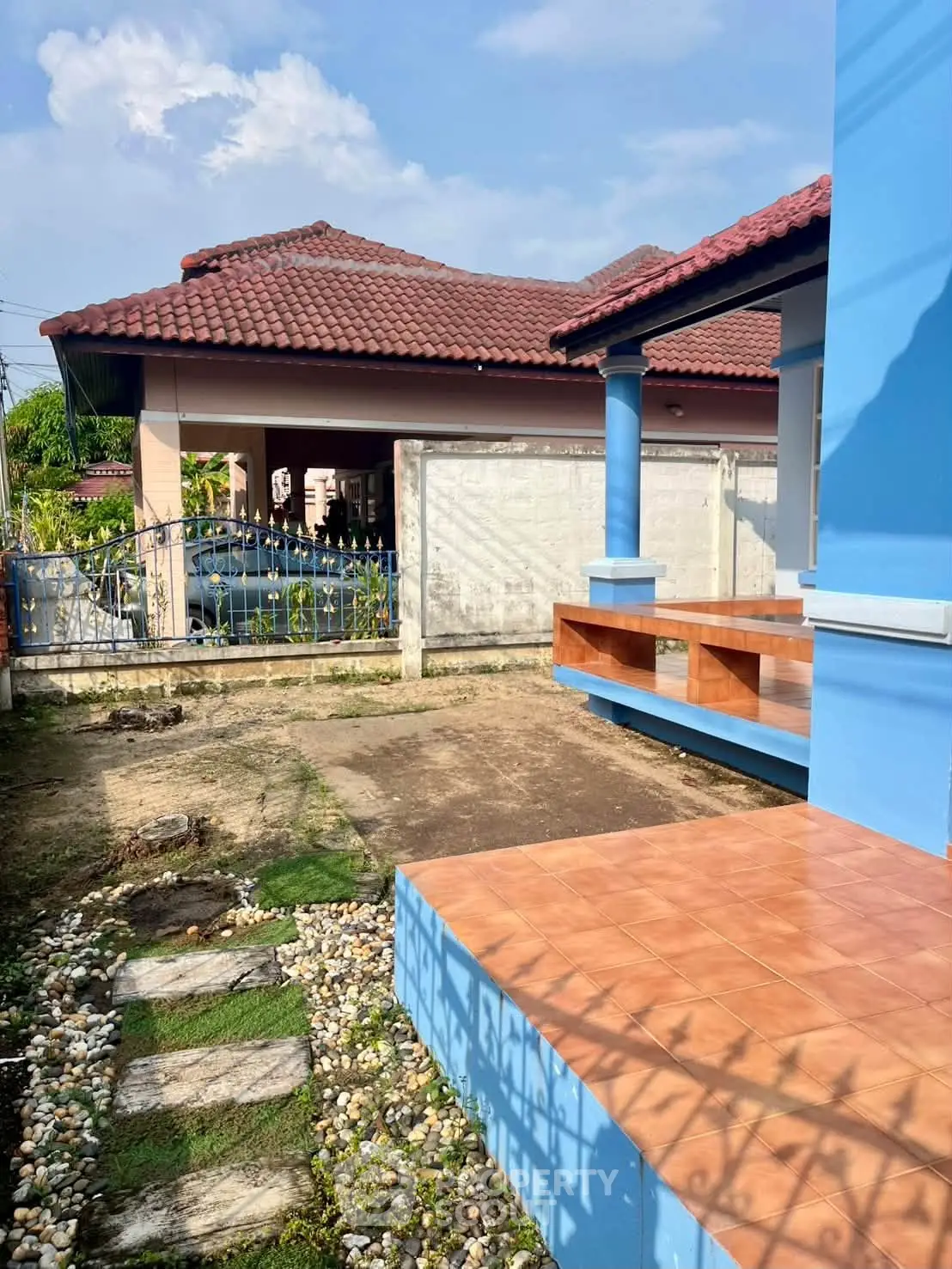 Charming blue house with tiled porch and garden path, perfect for family living.