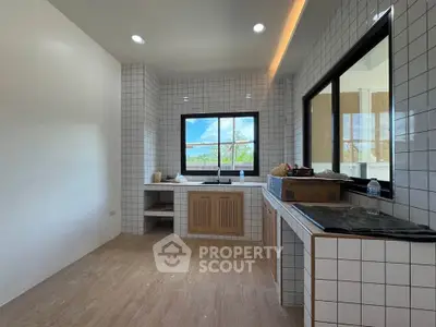 Modern kitchen with tiled walls and large window offering scenic views.