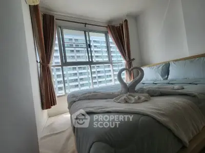Cozy bedroom with large window and elegant swan towel decor, offering a serene view of the cityscape.