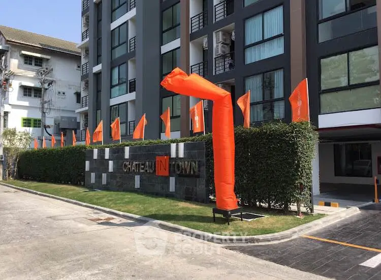 Modern apartment building with vibrant orange flags and lush greenery
