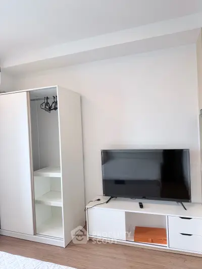 Modern bedroom with sleek wardrobe and flat-screen TV on stylish stand.