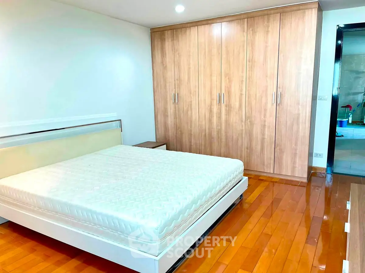 Spacious bedroom with wooden flooring and built-in wardrobe, perfect for modern living.