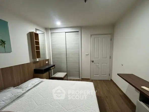 Modern bedroom with minimalist design and wooden flooring, featuring a cozy bed and built-in closet.