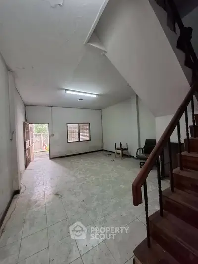 Spacious interior with staircase and tiled flooring, ideal for renovation or customization.