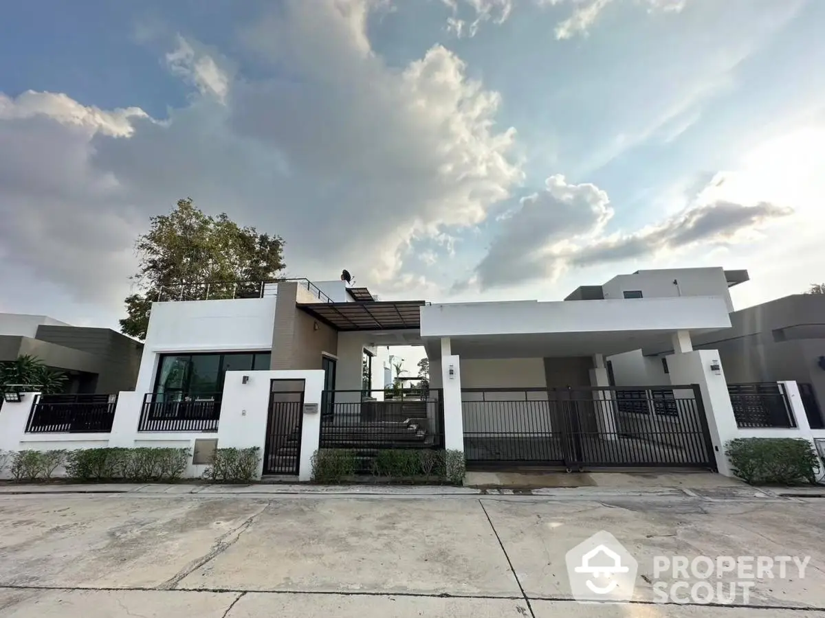 Modern single-story home with sleek design and spacious driveway under a cloudy sky.