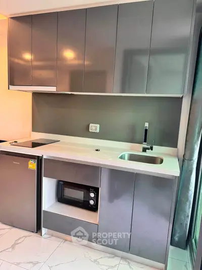 Modern kitchen with sleek cabinetry, built-in microwave, and compact fridge in stylish apartment.