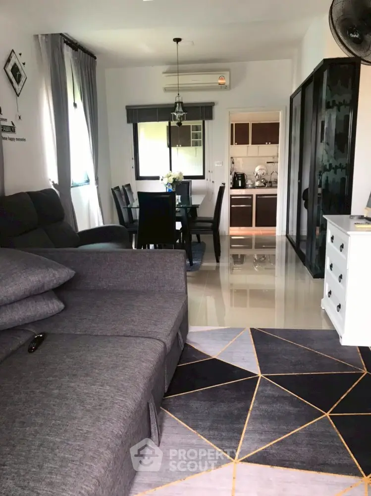 Modern living room with stylish furniture and open view to dining area and kitchen.