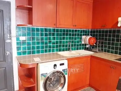 Charming kitchen with vibrant green tile backsplash and built-in washing machine.