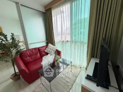 Cozy living room with red sofa, glass coffee table, and large window with green view.