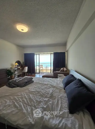 Spacious bedroom with ocean view and balcony access, featuring modern decor and cozy ambiance.