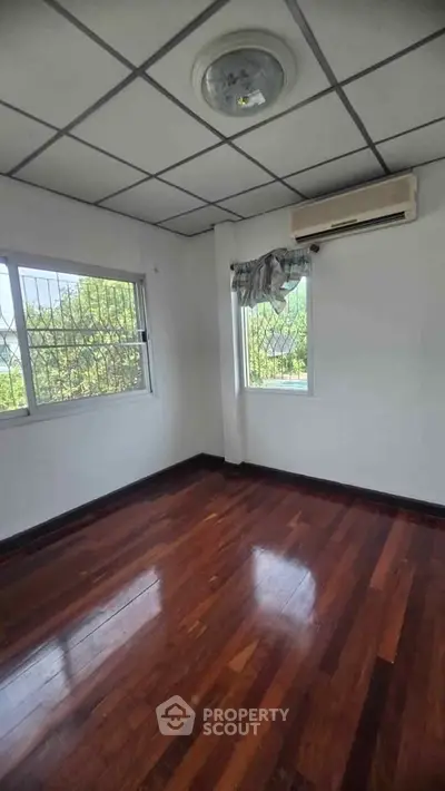 Spacious room with wooden floors and large windows offering natural light.