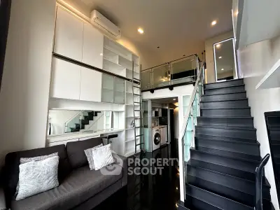 Modern loft apartment with sleek black staircase and built-in storage, featuring a cozy living area and washing machine.