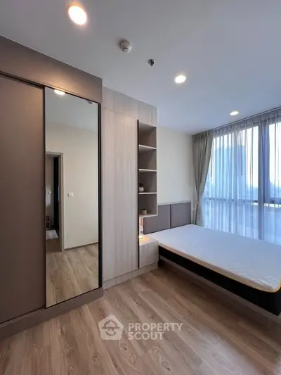Modern bedroom with large window and sleek wooden flooring