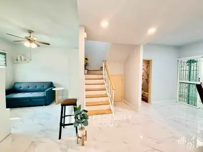 Spacious modern living area with elegant staircase and cozy seating.