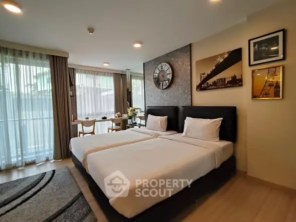 Spacious modern bedroom with twin beds and stylish decor, featuring large windows and natural light.