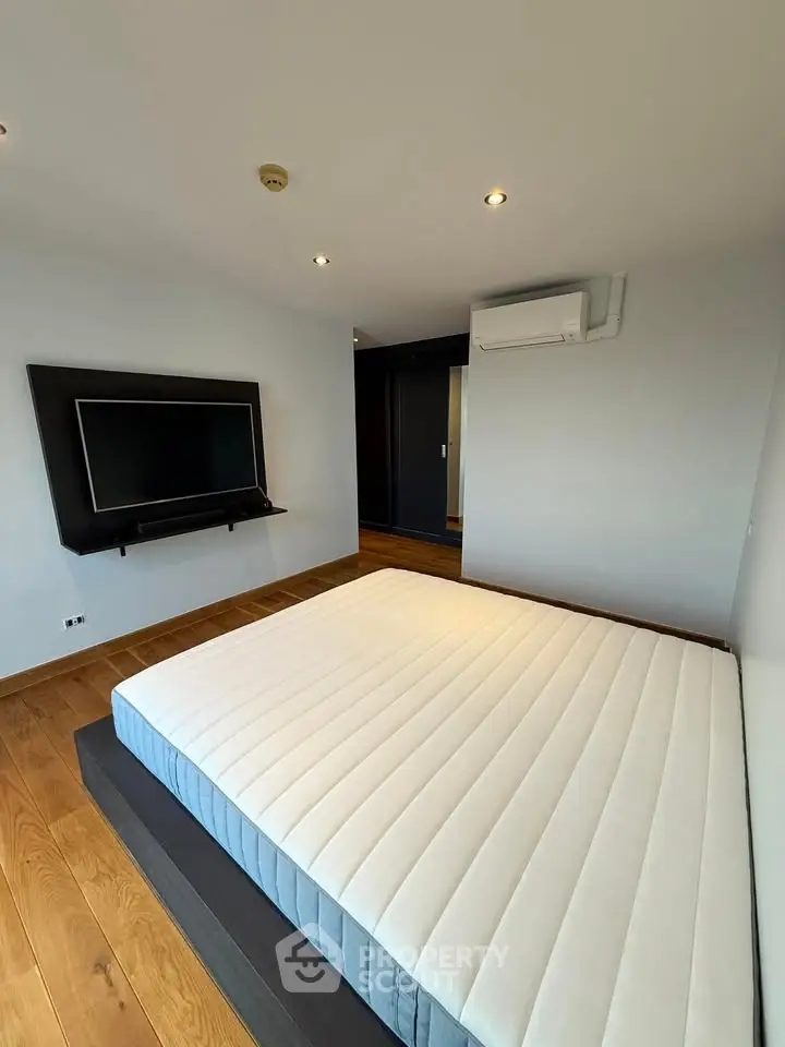 Modern bedroom with minimalist design and wall-mounted TV