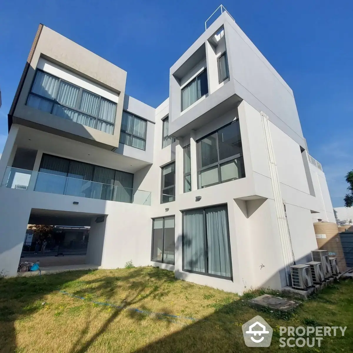 Modern multi-story residential building with large windows and a mix of flat and cantilevered roofs, showcasing a contemporary design with ample natural light.