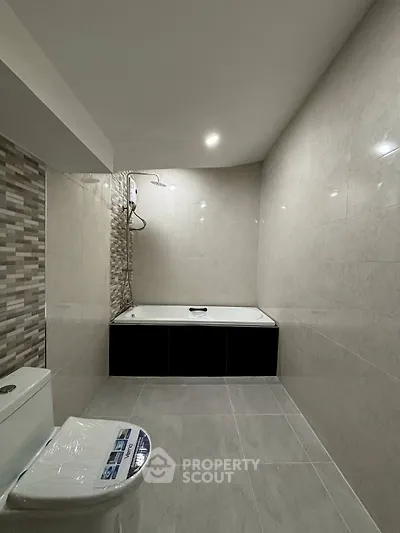 Modern bathroom with sleek tiles and built-in bathtub in a contemporary apartment.