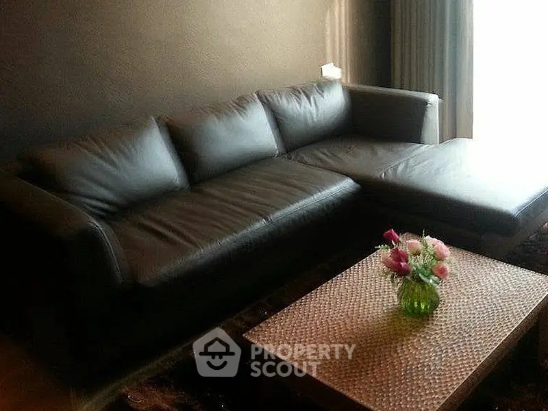 Stylish living room with sleek black leather sofa and elegant woven coffee table.