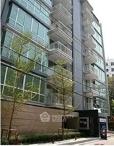 Modern apartment building exterior with glass balconies and sleek design.