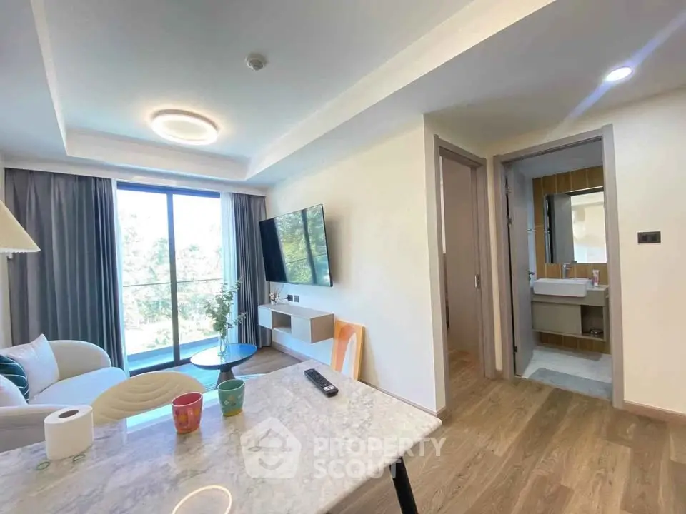 Modern living room with open layout and balcony view, featuring stylish furniture and natural light.