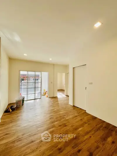Spacious empty living room with wooden flooring and large windows