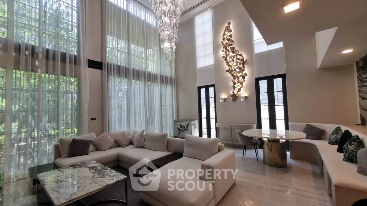 Luxurious living room with high ceilings, elegant chandelier, and modern decor in a spacious open layout.