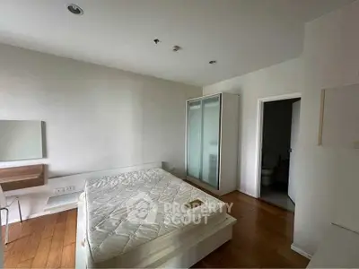 Spacious bedroom with wooden flooring and modern furniture