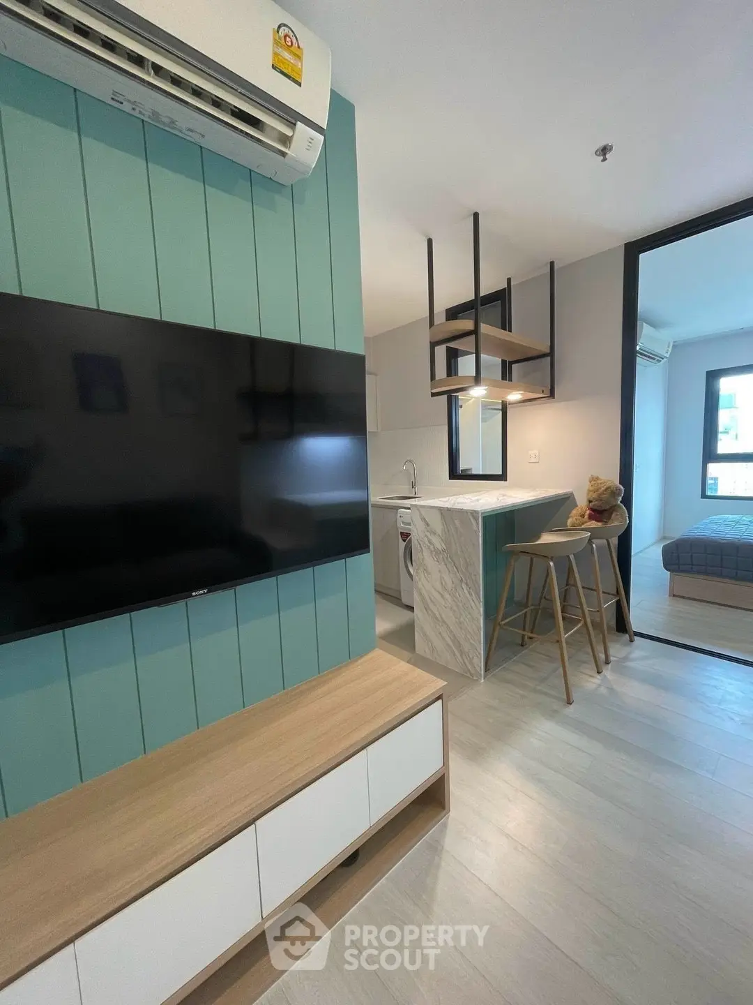 Modern open-plan living room with stylish kitchen and cozy bedroom view.