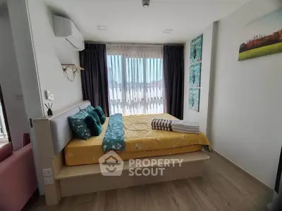 Cozy bedroom with modern decor and large window offering natural light and scenic view.
