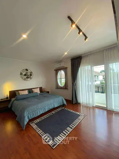 Spacious bedroom with elegant decor and large windows offering natural light.