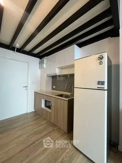 Modern kitchen with sleek design and wooden flooring, featuring a fridge and open shelving.
