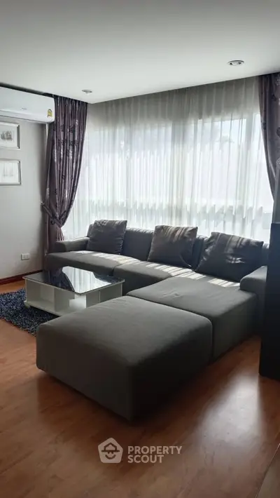 Stylish living room with modern gray sectional sofa and large windows.