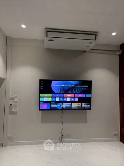 Modern living room with wall-mounted TV and air conditioning unit, showcasing sleek design and technology.