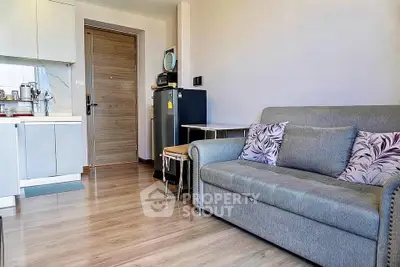 Modern living room with cozy sofa and compact kitchen in open layout apartment.