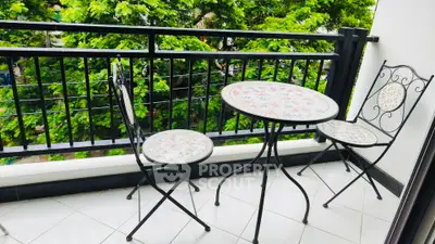 Charming balcony with elegant wrought iron furniture and lush green view.