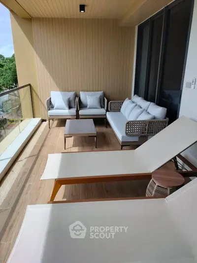 Spacious balcony with modern outdoor furniture and scenic view, perfect for relaxation.