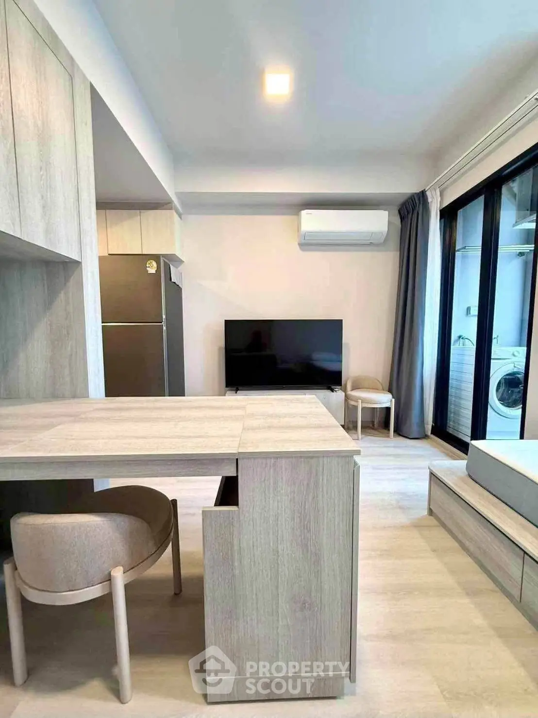 Modern living room with sleek furniture and balcony view, featuring a washing machine and air conditioning.