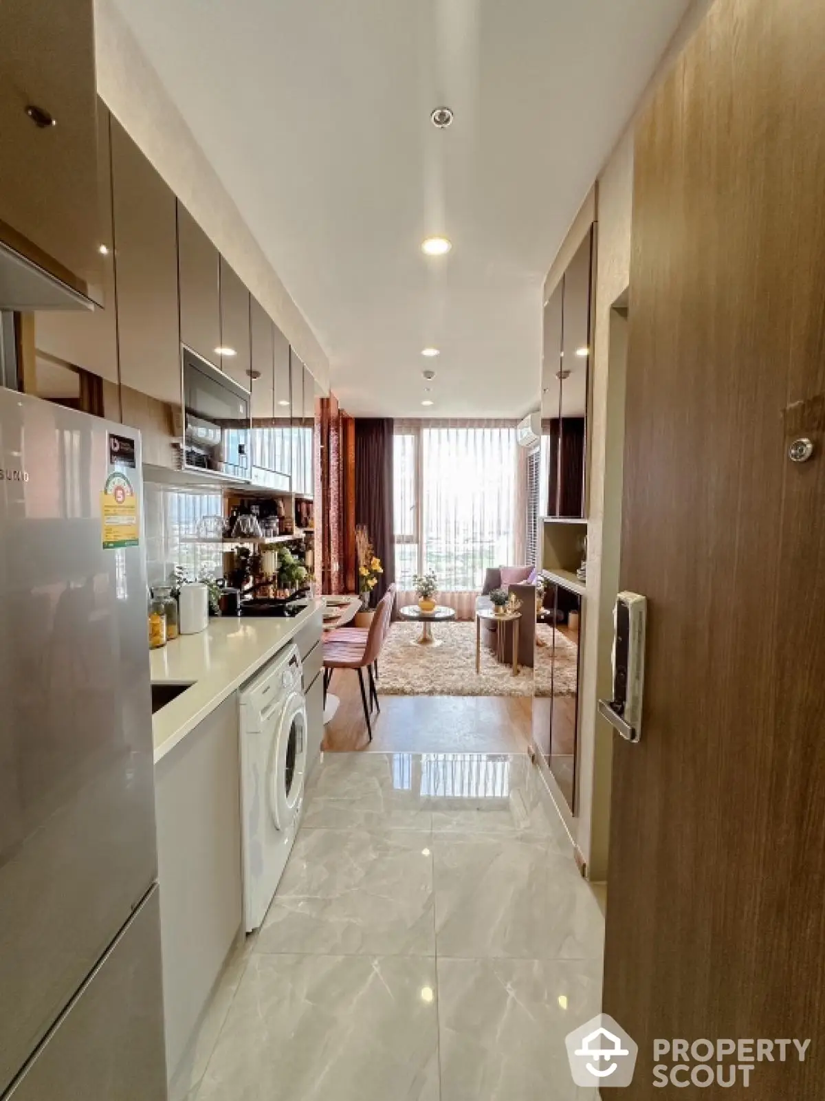 Modern kitchen with washing machine and open layout leading to stylish living area.