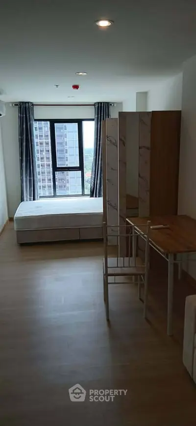 Modern bedroom with city view, featuring minimalist furniture and large window for natural light.