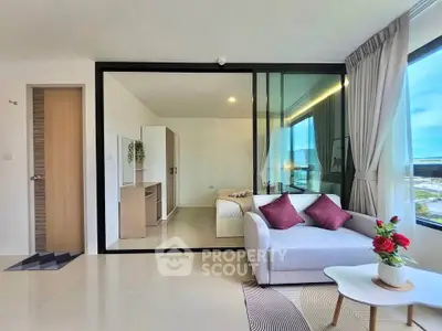 Modern living room with glass partition, cozy sofa, and bright natural light