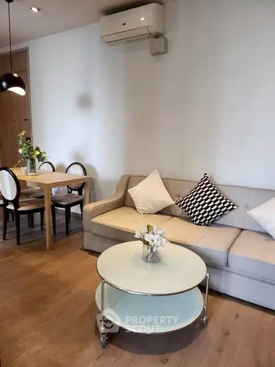 Modern living room with stylish sofa and dining area, featuring elegant decor and wooden flooring.