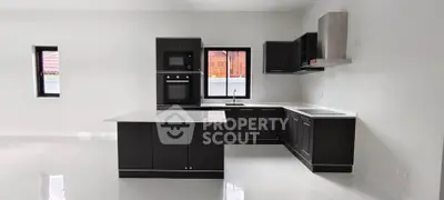 Modern kitchen with sleek black cabinetry and white countertops in a spacious open layout.