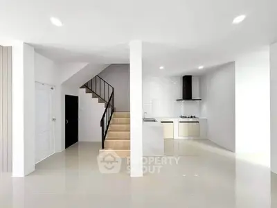 Modern open-plan kitchen with sleek staircase and minimalist design