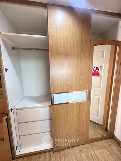 Spacious wooden wardrobe with sliding doors and mirror in modern apartment